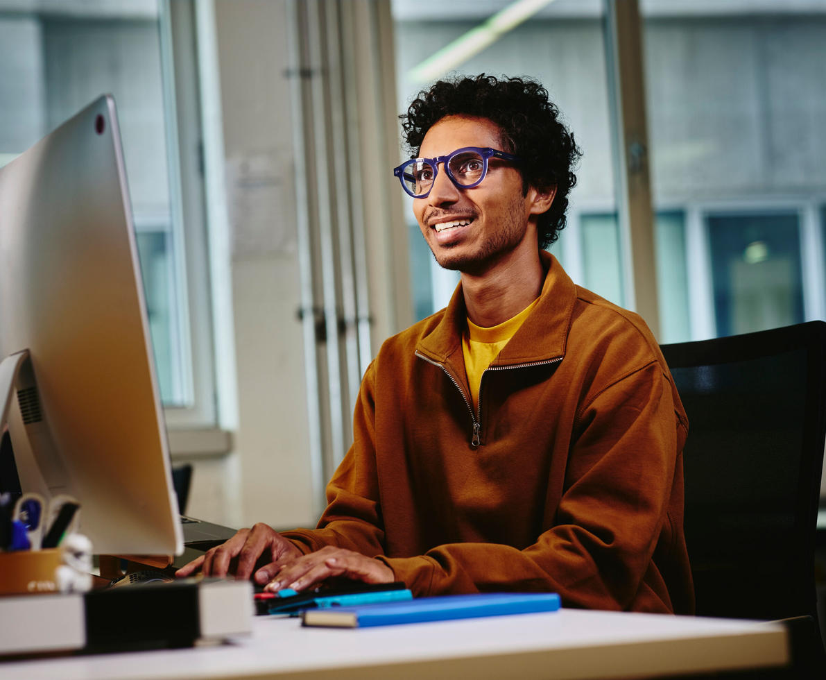 male looking up a computer screen sitting at a desk